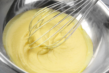 Cheese sauce in metal bowl and corolla, closeup