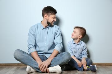 Father and his son sitting on floor near color wall
