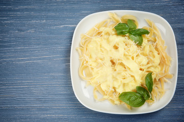 Portion of delicious pasta with cheese on wooden background