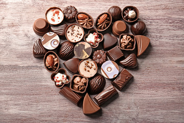 Heart-shaped collection of chocolate candies on wooden background