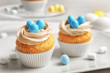 Delicious Easter cupcakes on grey plate against blurred background