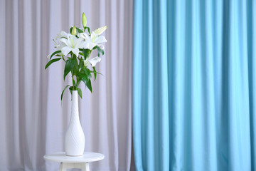Fototapeta na wymiar Beautiful white lilies in vase on curtain background