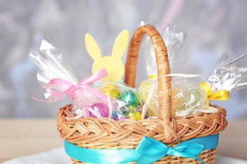 Fototapeta premium Easter basket with sweets and presents on blurred background