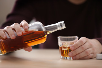 Handsome depressed man drinking whisky at home