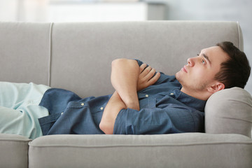 Handsome depressed man on couch at home