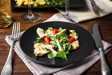 Delicious dinner with chicken, arugula, spinach and basil on black plate