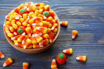 Bowl with tasty Halloween candies on wooden background