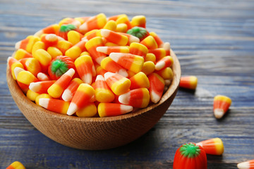 Bowl with tasty Halloween candies on wooden background