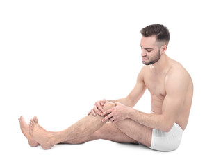 Young man suffering from pain in knee on white background