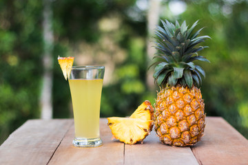 glass of pineapple juice with green nature background