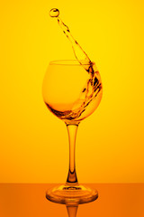 Splash of water in a glass on yellow