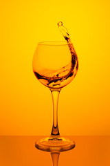 Splash of water in a glass on yellow