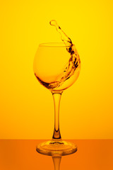 Splash of water in a glass on yellow
