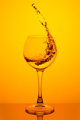 Splash of water in a glass on yellow