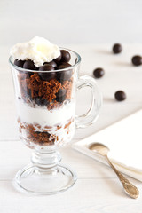 Layered dessert with with a filbert in chocolate, a biscuit, a chocolate crumb and creamy ice cream in glass jar, selective focus