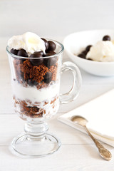 Layered dessert with with a filbert in chocolate, a biscuit, a chocolate crumb and creamy ice cream in glass jar, selective focus