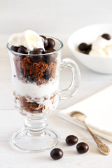 Layered dessert with with a filbert in chocolate, a biscuit, a chocolate crumb and creamy ice cream in glass jar, selective focus