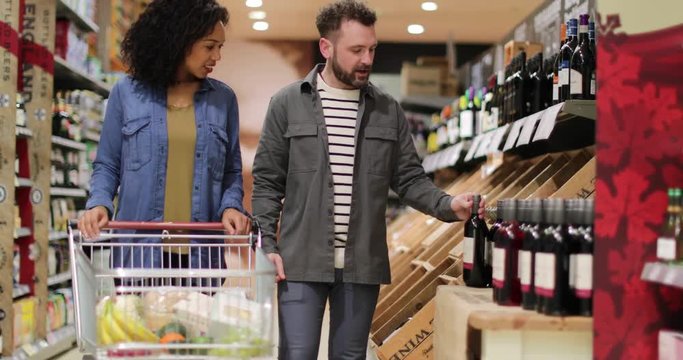 Couple choosing wine in grocery store
