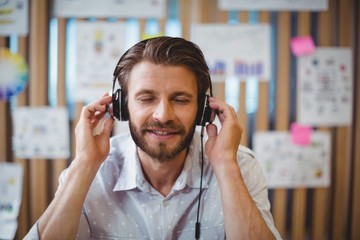 Close-up of male graphic designer listening music on headphone