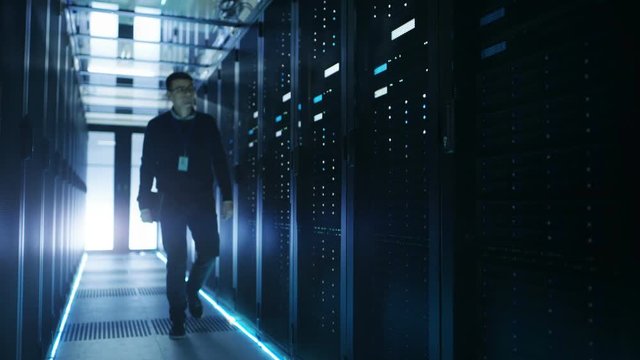  IT Engineer Holding Notebook and Walking Through Data Center Full of Working Rack Servers.  Shot on RED EPIC-W 8K Helium Cinema Camera.