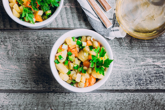 Healthy Vegetable salad with potato,carrot,pears and green onion in a white bowl on wooden table. Vegetarian food content. Top view, copy space