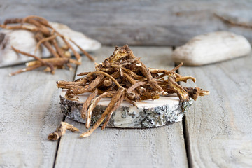 Dried dandelion root on a wood background. Selective focus
