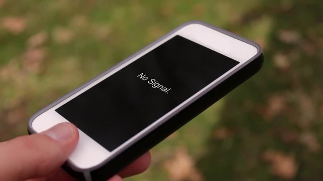 A phone with a no signal text on the screen in an outside environment