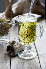 Cup of fresh herbal tea (Dried  Thymus) on wooden table. The frozen movement. Selective focus.