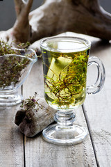 Cup of fresh herbal tea (Dried  Thymus) on wooden table.  Selective focus.