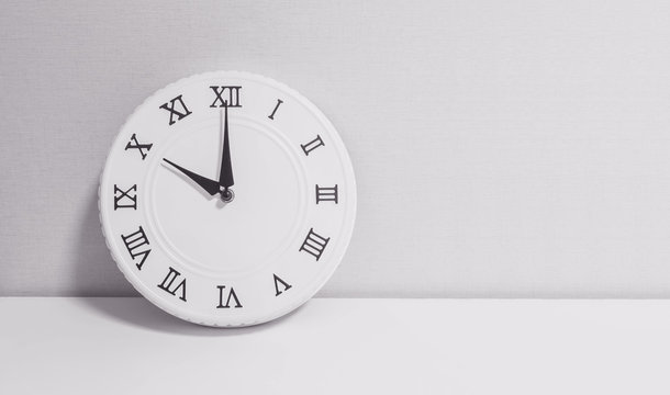 Closeup white clock for decorate in 10 o'clock on white wood desk and wallpaper textured background in black and white tone with copy space