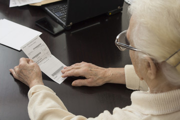 Stara siwa kobieta u lekarza. Staruszka trzyma w dłoniach receptę i czyta    