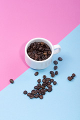 White cup with coffee beans on a colored background	