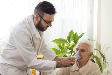 Lekarz trzyma inhalator przy twarzy starej kobiety. Atak astmy. Inhalacja górnych dróg oddechowych.  Lekarz w gabinecie przeprowadza inhalację.