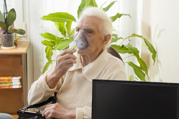 Stara kobieta podczas inhalacji. Pacjentka trzyma maseczkę inhalatora. Atak astmy. Inhalacja górnych dróg oddechowych.  - obrazy, fototapety, plakaty