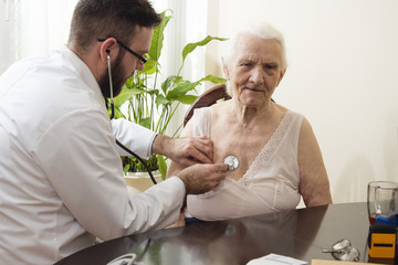 Lekarz bada stetoskopem starą kobietę w gabinecie lekarskim. Badanie lekarskie stetoskopem. Lekarz geriatra bada płuca. - obrazy, fototapety, plakaty