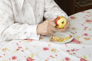 Obraz na płótnie Canvas Dłonie starej kobiety obierającej jabłko.