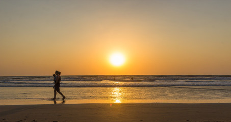 Fototapeta na wymiar Woman are walking at sunseton Arambol beach, Goa, India