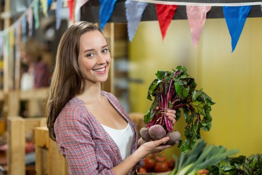 Smiling woman choosing vegetables in grocery store