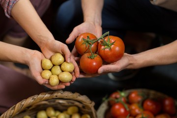 vendors holding tomatoes and potatoes at grocery 