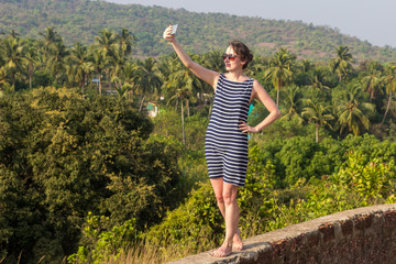 Fototapeta premium Young woman is making a selfie photo from a mobile phone, Goa, India