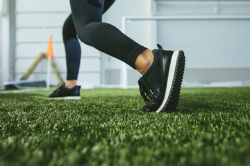 Young woman in sportswear is engaged in the sports stadium closeup of feet