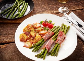 Meal of asparagus, poscuitto and potatoes on plate