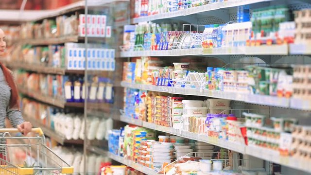 Woman chooses butter and sausage in the supermarket