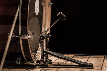 percussion instrument, bass drum with pedal on wooden boards with a black background - obrazy, fototapety, plakaty