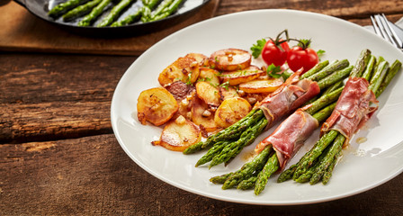 Meal of asparagus, poscuitto and potatoes on plate