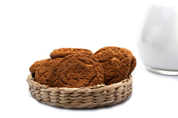 Oatmeal cookies in a wicker basket and a jug of milk. isolated