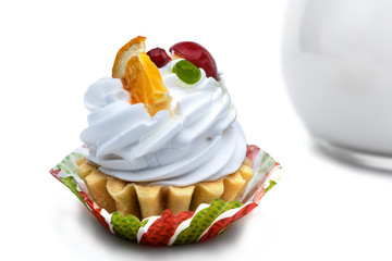 cake basket with cream garnished with fruits on a background of a jug of milk. isolated