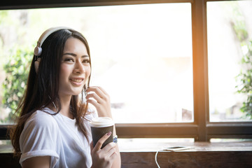 Young attractive woman listening music in headphones on windowsill background. Women lifestyle concept.