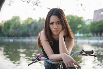 Obraz premium Beautiful young woman riding bicycle in green park.