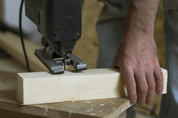 Man cutting wood block with fretsaw at the workshop